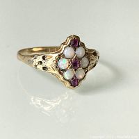 Front-angle view of ring showing five opals and three rubies in cluster, engraved shoulders