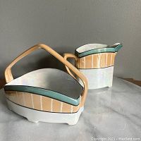 Creamer and sugar bowl set photographed on marble surface against beige wall, showing both pieces clearly to display colors, finish, and design details.