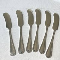 Full set of six Birks sterling silver butter knives with bead design handles laid out on white surface.