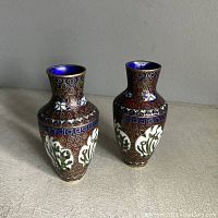 Two small Chinese cloisonne vases side by side showing detailed floral patterns with red, blue, white, and green enamel and blue interior glaze.