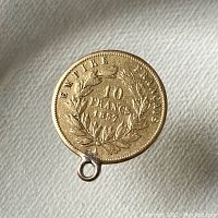 Reverse side of coin pendant showing wreath and inscription 'EMPIRE FRANÇAIS 10 FRANCS 1857' with loop at bottom.