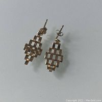 Pair of 10K gold triangular articulating link earrings displayed on a white surface showing the front view of the geometric woven grid design.