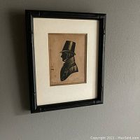 Framed silhouette portrait of a man in a top hat shown mounted on a wall.