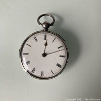 Front view showing white dial with black Roman numerals and hands.