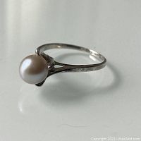 Close-up side angle of silver ring with grey-blue pearl showing setting details
