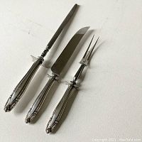 Full view of 3-piece carving set including knife, fork, and sharpener with silver handles showing intricate pattern.