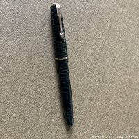 Full view of the Parker Vacumatic fountain pen showing green striped pattern body and cap with metallic clip.