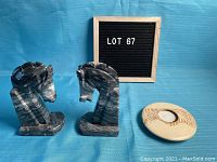 Two dark marbled horse head bookends and one light-colored ceramic tealite holder shown against blue background with lot number