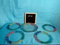 Five handcrafted colored glass plates arranged on blue fabric background with a LOT 20 sign.