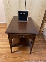 Front view of wooden end table showing drawer and lower shelf.
