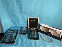 Photo of all items in the lot including four boxed sets of acrylic handled cheese servers and salad tongs, and four clear glass leaf-shaped luncheon plates, with two plates shown outside original packaging.