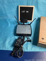 Front and top view of the Linksys WRT350N router showing antennas and power adapter with cords coiled.