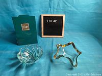 Two clear glass candy dishes on blue background. Left is a swirl pattern Mikasa candy dish. Right is a star-shaped clear glass candy dish with gold trim, showing some wear and etched artist name on bottom.