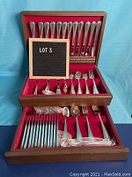 Wooden silverware case open showing top lid knives, middle and bottom trays of utensils