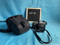 Photo of Pentax P30 camera body with lens attached and black camera case on blue surface with lot number board
