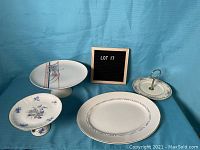 Four porcelain plates set including three cake plates and one serving plate on a blue backdrop.