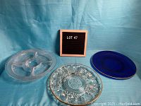 Set of three plates shown on blue fabric background including the deviled eggs plate, the veggie and dip plate, and cobalt blue plate