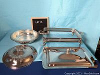 Photo of two silver plated chafing dishes with lids, one round with glass insert, one rectangular missing glass lasagna pan, and the salt & pepper set
