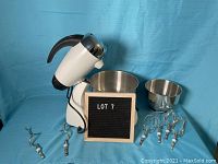 Full view of white Sunbeam Mixmaster with two bowls and all attachments laid out on blue background with a lot sign.
