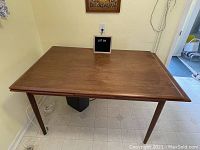 Top-down view of closed rectangular teak tabletop showing wood grain and surface condition
