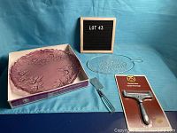 Full set including purple/pink decorative plate, clear cheese plate, two cheese slicers, and lot number board.