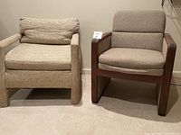 Two low armchairs positioned side by side against a wall, one with woven upholstery and the other with wooden frame and fabric cushions.