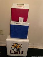 Photo showing three coolers: LSU styrofoam cooler at bottom, blue Coleman cooler in middle, red and white Little Playmate cooler on top.