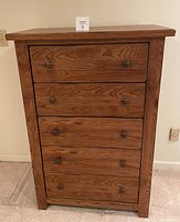 Front view of the 5-drawer wooden dresser showing all drawers closed with metal knob handles and oak finish.