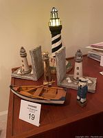 Full lot showing the light-up lighthouse, sailor figurine, sailboat model, and lighthouse bookends.