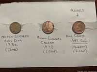 Front view of three coins taped to a paper with handwritten details: 1982 Hong Kong dime, 1978 Canadian 1 cent, 1947 Canadian 1 cent (King George VI).