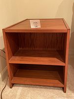 Front view of wooden side table showing two shelves and open space.