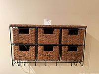 Front view of wicker shelf unit showing six wicker drawers and six metal hooks beneath.