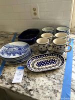 Photo showing blue and white ceramic dishes on counter including bowls, Manufaktura mugs, plates, and Chantal baking dish.