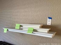 White floating wall shelves stacked and visible from a distance, showing size and condition.