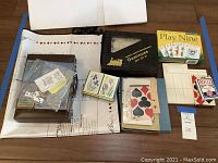 Assorted boxed and loose card and dominoes sets laid on a table, various game materials visible.