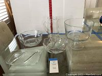 Photo showing entire lot with five glass serving pieces including trifle bowl, two bowls, divided tray, and pitcher.