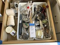 Overview of drawer contents showing various kitchen tools arranged in tray with measuring cups, grater, slicer, timer and more.