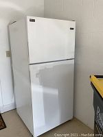 Frontal right angle view of the white Maytag top freezer refrigerator showing two-door design and warranty sticker