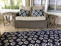 Couch with cushions and decorative pillows flanked by two wicker end tables