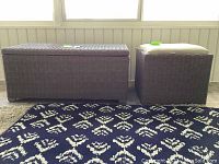 Front view of two plastic wicker storage pieces, a larger storage chest and a smaller cushioned seat.