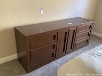 Full view of the brown painted wood dresser with central cabinet and drawers, showing its size and wear.