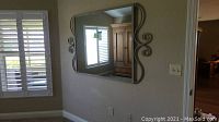 Mirror hung on wall showing overall size and frame style with window reflection.