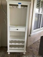 Full front view of white wooden wine cabinet with glass rack, drawer, and wine bottle rack