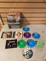 Photo displaying multiple loose game discs laid out on a surface, mostly Nancy Drew titles and some other game discs for various platforms.