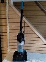 Full view of Bissell PowerForce Compact vacuum cleaner standing upright with handle extended, showing base and dust container.