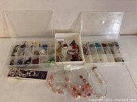 Overview of costume jewelry and beads in plastic storage boxes with clear lids and loose beaded bracelets.