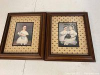 Two folk art children prints framed and matted, shown side by side on a white surface.