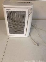 Front view of the Holmes air purifier showing the white perforated panel and control knob with power cord.