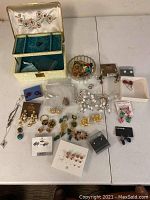 Full shot of assorted jewelry spread on surface with open jewelry box showing