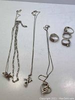 Image showing multiple sterling silver necklaces and assorted rings including chain necklaces and various style pendants, plus wedding set rings with CZ.
